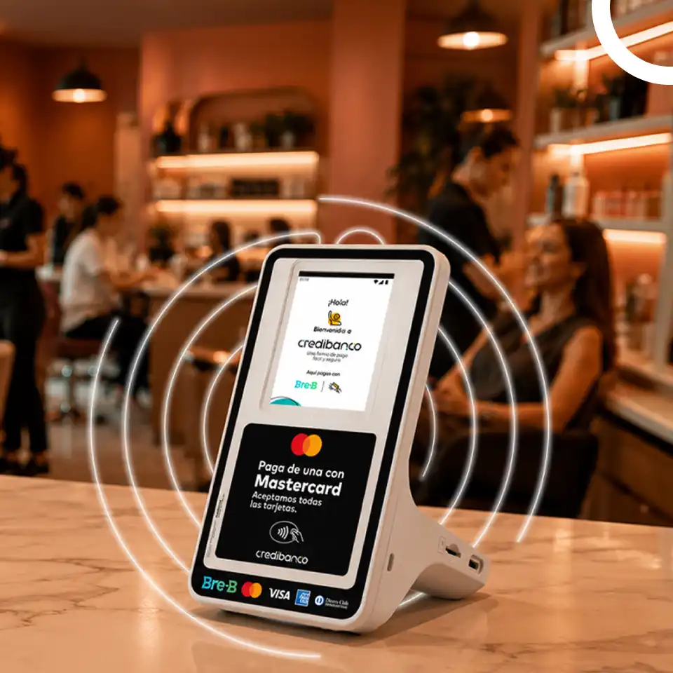Terminal de pago Credibanco sobre el mostrador de un restaurante o cafetería, con pantalla que muestra opciones de pago con tarjeta Mastercard, rodeado de ondas luminosas que representan tecnología de pago sin contacto.