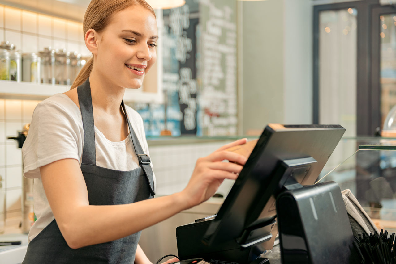 Cheerful,Shop,Assistant,Using,Digital,Device,For,Payment