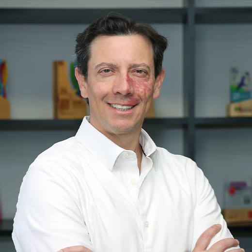 FOTO-FELIPE Hombre de mediana edad con camisa clara, sonriendo, en un retrato tipo corporativo con fondo neutro.