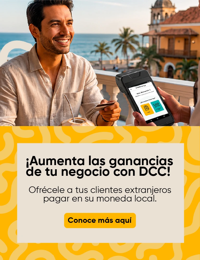 Cliente sonriente en una terraza frente al mar realiza un pago con tarjeta mientras un empleado sostiene una terminal de cobro. En la parte inferior aparece el mensaje: ‘¡Aumenta las ganancias de tu negocio con DCC! Ofrécele a tus clientes extranjeros pagar en su moneda local’ y un botón que dice ‘Conoce más aquí’.